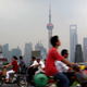 Commuters ride bicycles and scooters as they cross a bridge in down town Shanghai